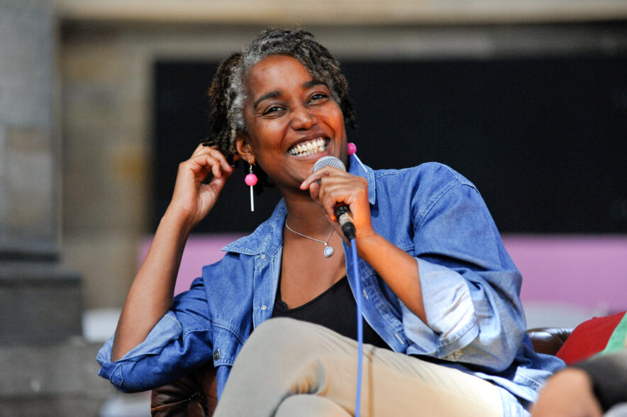 Smiling headshot of woman sitting back in a chair, holding a microphone